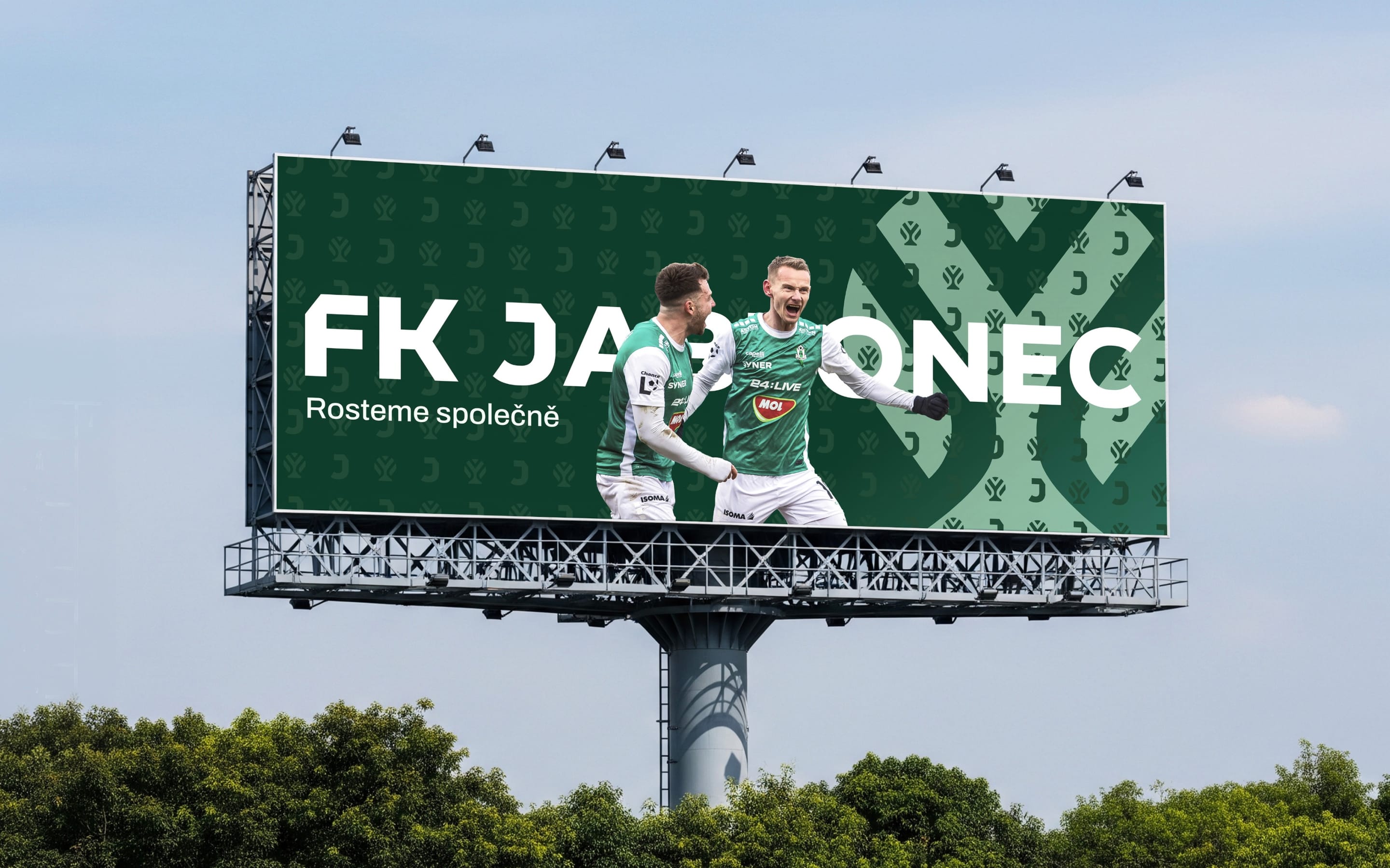 An FK Jablonec billboard above trees: two players celebrating in green kits beside the claim Rosteme společně.