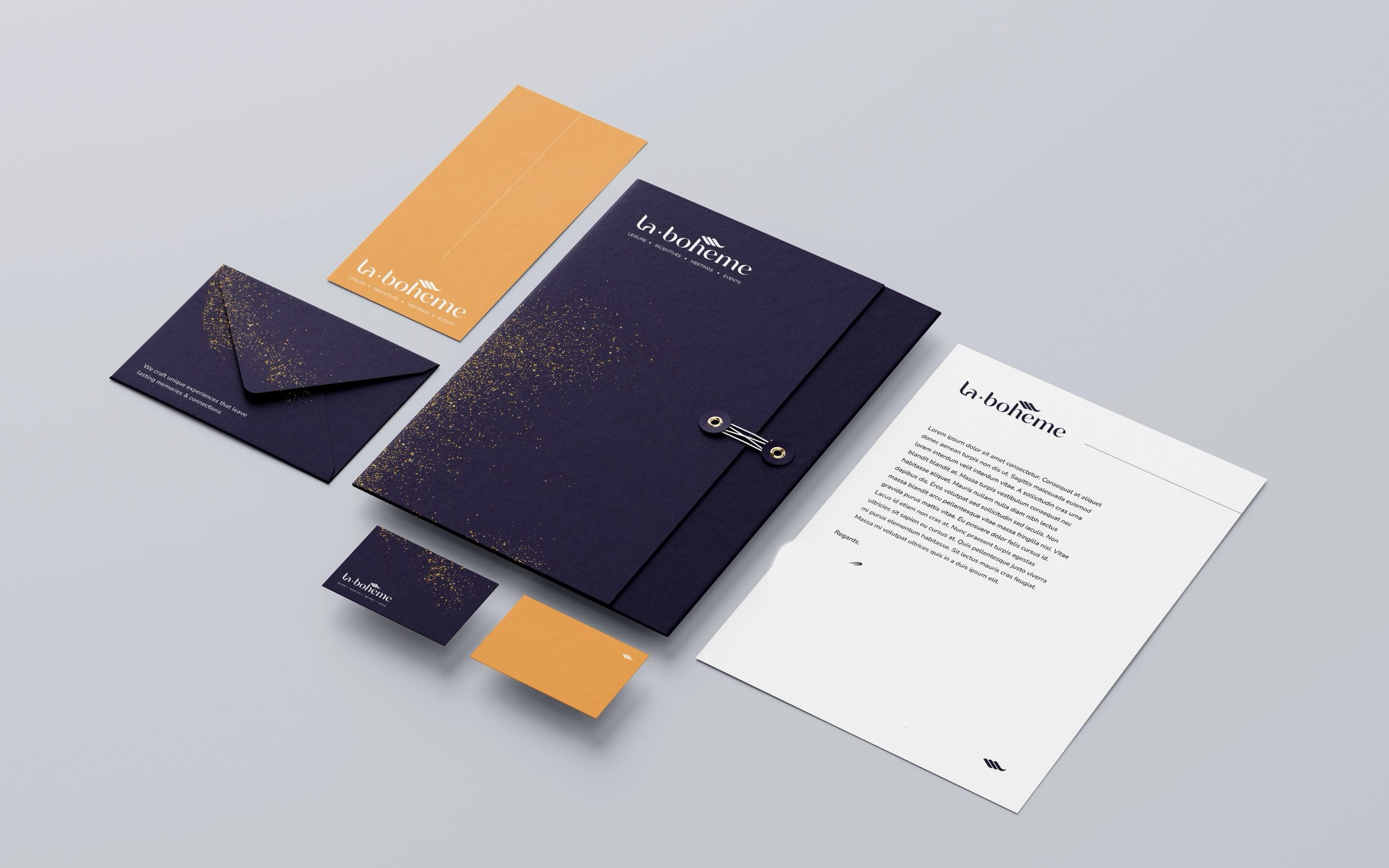 La-Bohème stationery on grey: a deep purple folder, envelope and card with gold speckles, coral cards and a letterhead.