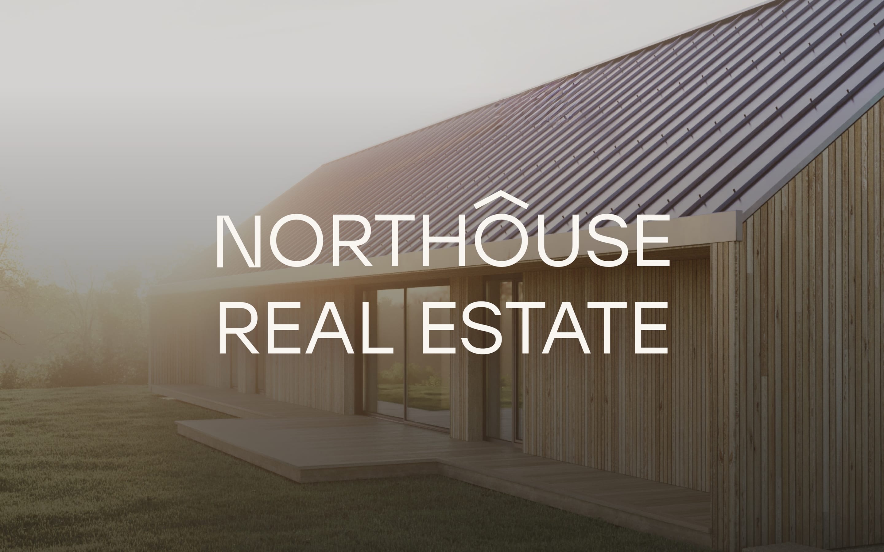 The Northouse Real Estate wordmark over a timber house with a dark metal roof in morning mist.