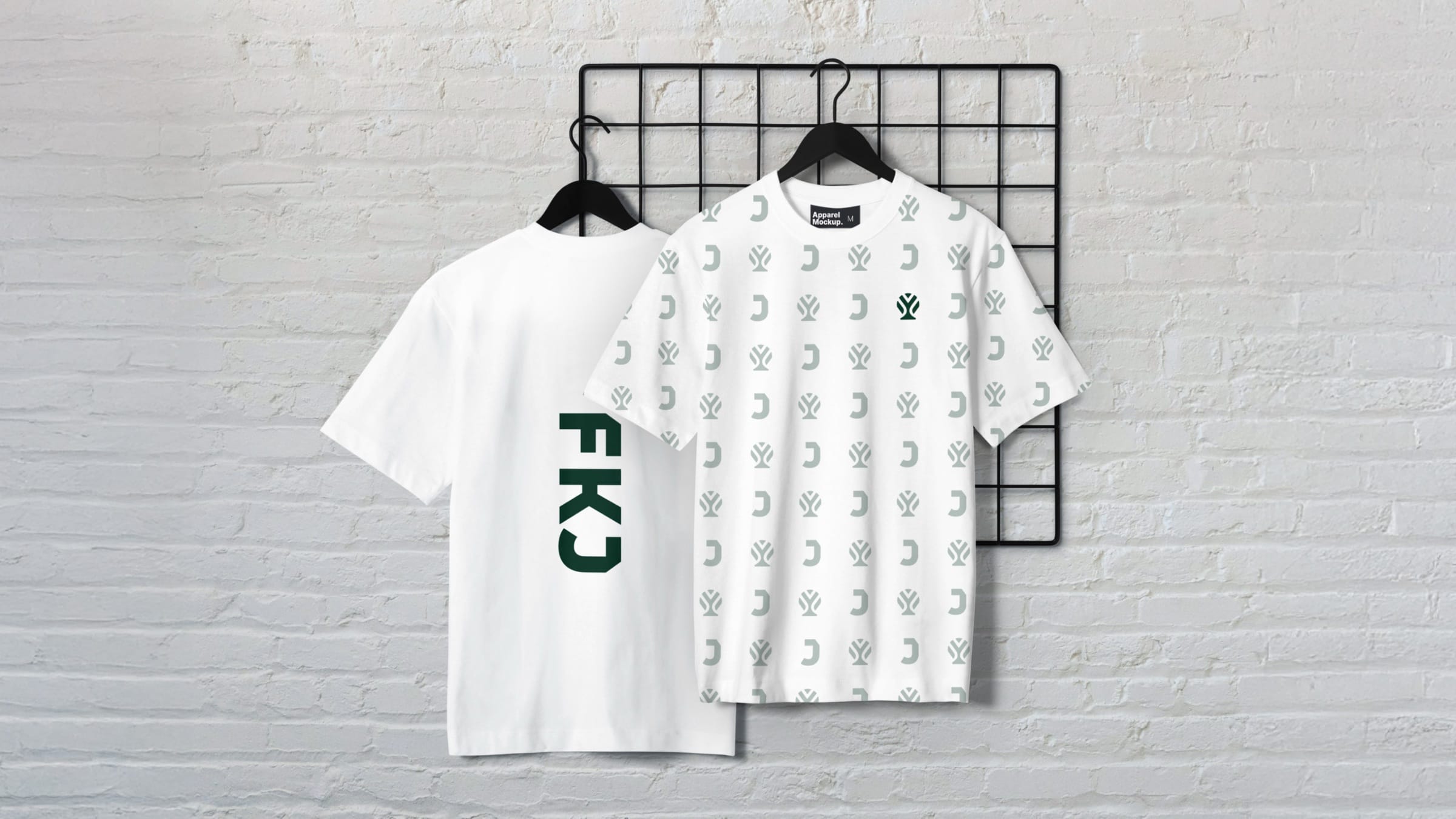 Two white T-shirts on a wire grid: one with a vertical FKJ wordmark, one covered in the J and tree pattern.