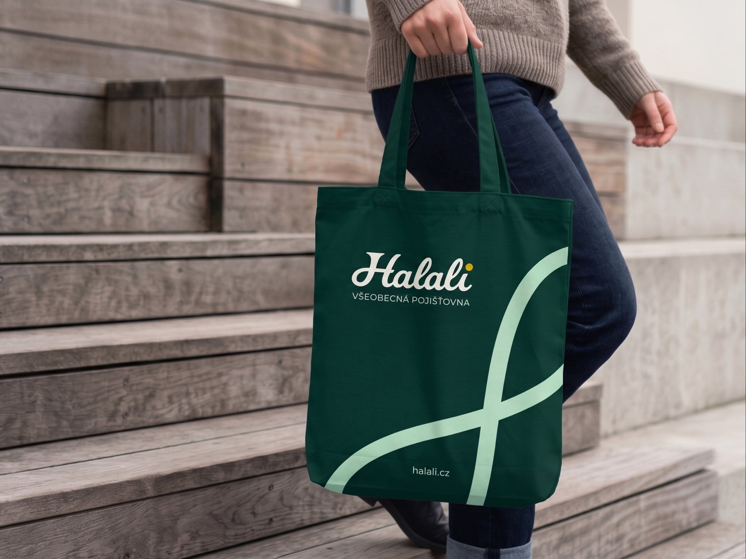 A person walks down wooden steps carrying a Forest Teal tote bag with the Halali logo and a mint loop.