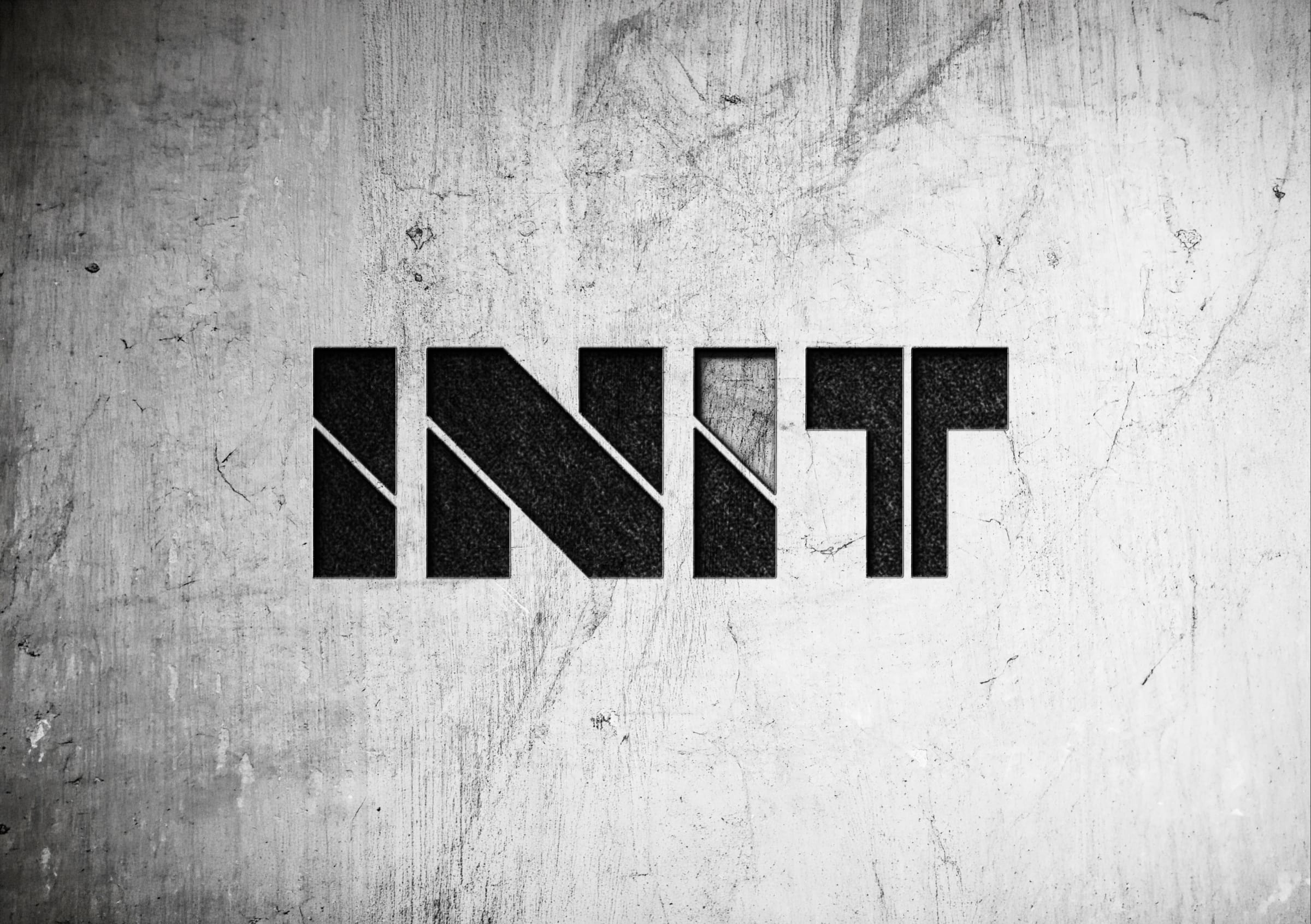 The INIT logotype cut deep into a scratched, pale concrete surface, the top of the second I left raw.